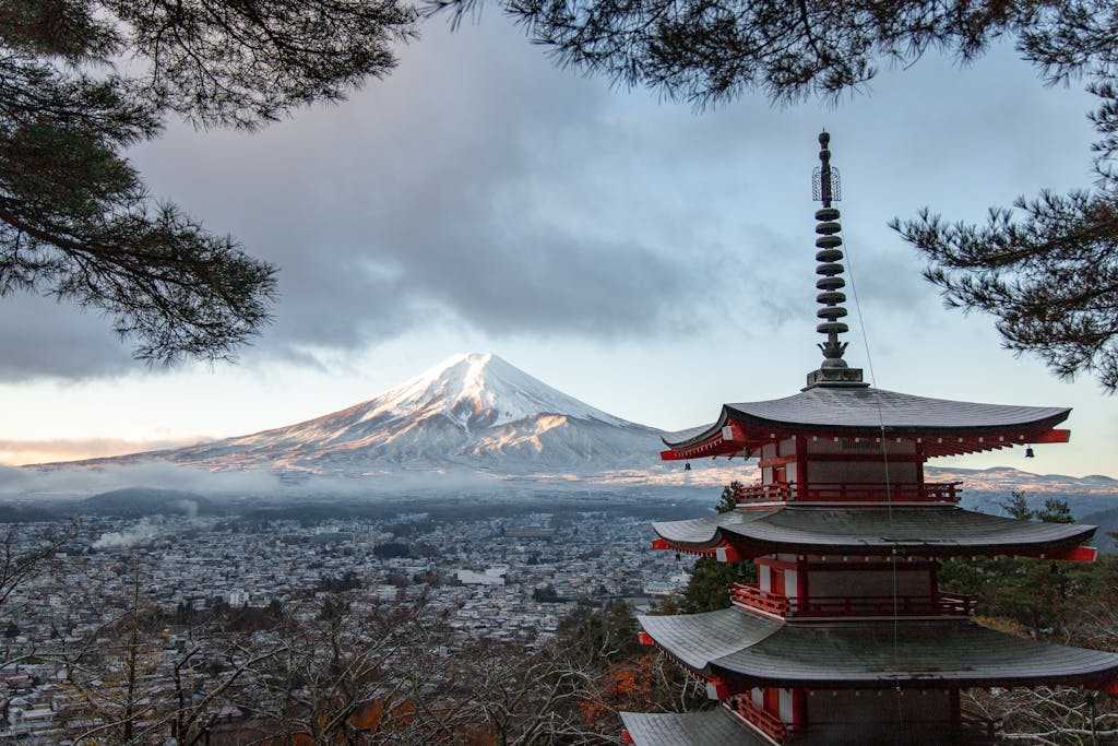 Scenic view of Chureito Pagoda with snow-capped Mount Fuji under a cloudy sky in Fujinomiya, Japan.